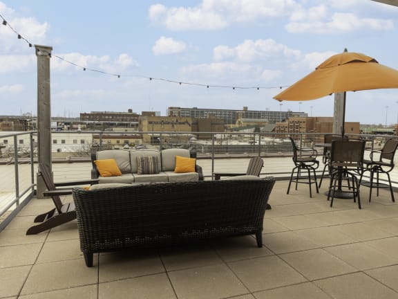 a rooftop patio with a couch and chairs and an umbrella