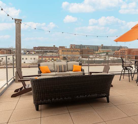 a rooftop patio with a couch and chairs and an umbrella