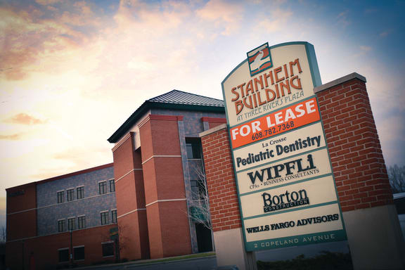 a sign building for lease with a building in the background
