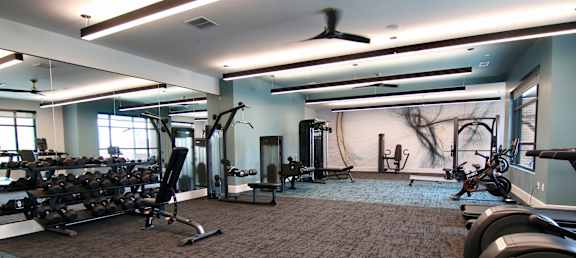 a gym with weights and other exercise equipment in a room with a large window