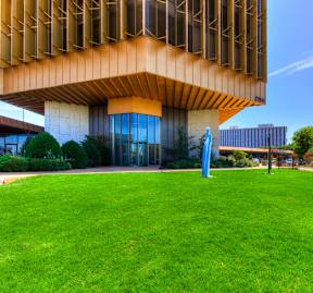 A modern building with a large grassy area in front.