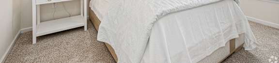 a bedroom with a large bed and a window at The Met Apartment Homes, Hattiesburg, 39402