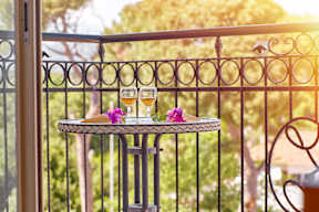 Two glasses of wine on a table with flowers on a balcony.