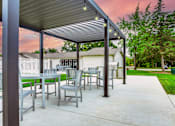 Thumbnail 5 of 5 - A patio with a table and chairs under a roof.