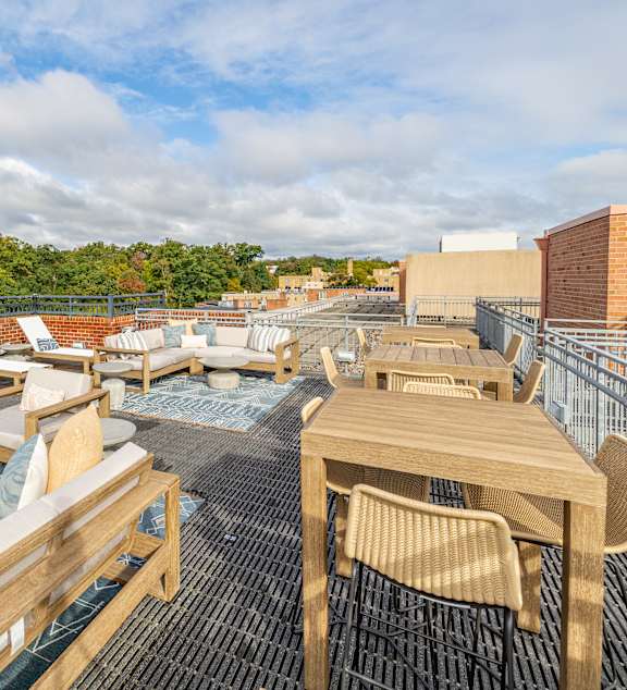 Rooftop terrace sundeck featuring modern outdoor lounge seating, dining tables, and scenic neighborhood views at The Barton at Woodley in Washington DC