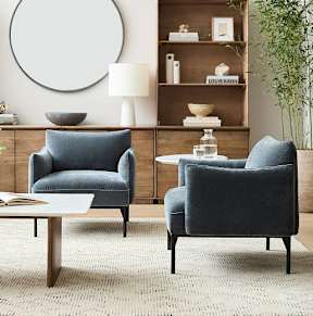 Two grey chairs and a table in a room with a round mirror on the wall.
