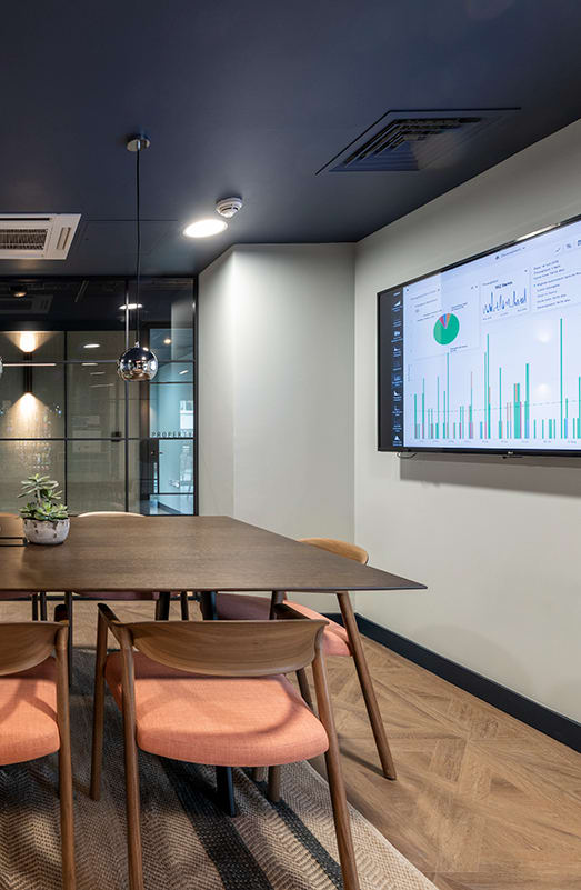 a conference room with a table and chairs and a screen on the wall