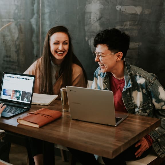a group of people sitting at a table with laptops