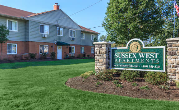 a picture of the sussex west apartments sign with a house in the background