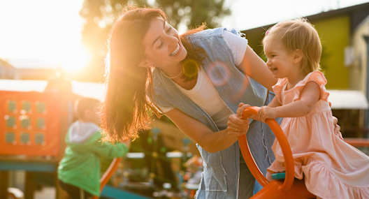 A woman and a child are playing with a toy car.