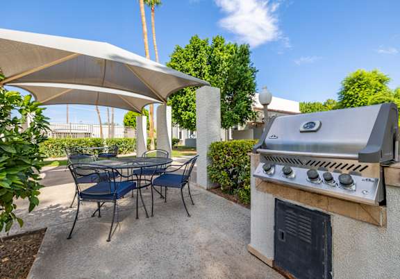 A patio with a grill and chairs under a white canopy.