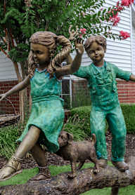Two children and a dog are on a log.