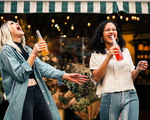 two women drinking beer in front of a store