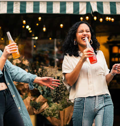 two women drinking beer in front of a store