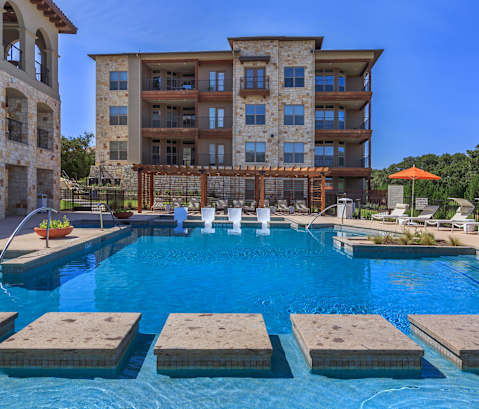 a resort style swimming pool with chaise lounge chairs and umbrellas in front of a