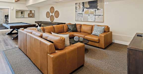 A brown leather couch with a blue pillow is in the center of a living room.