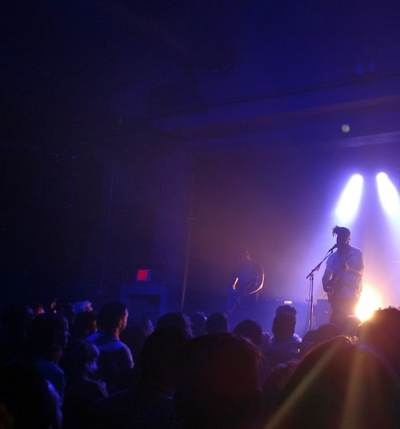A band performing on stage with bright lights shining down on them.