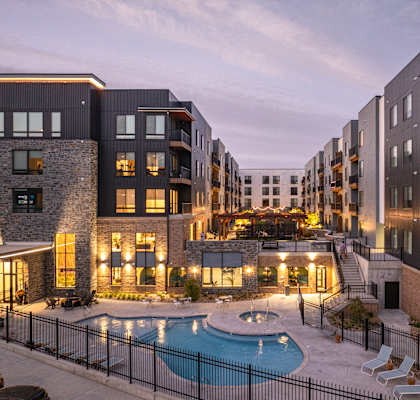 A row of modern apartment buildings with a pool in the courtyard.