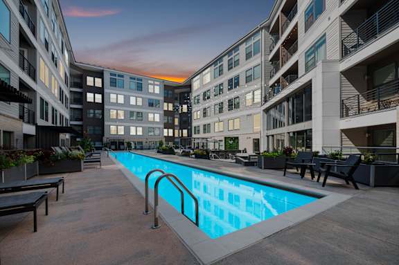 A swimming pool is surrounded by apartment buildings.