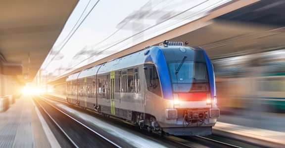 A blue train is in motion on the tracks.