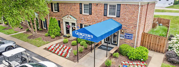 A building with a blue awning and a sign that says "Georgetown" is surrounded by a flower garden.