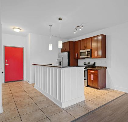 A kitchen with brown cabinets and a red door at River Mill Lofts & Skyloft in Asheville, North Carolina 28803