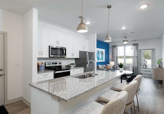 an open kitchen and living room with a granite counter top