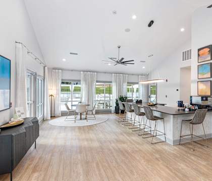 a living room with a kitchen and a bar with chairs