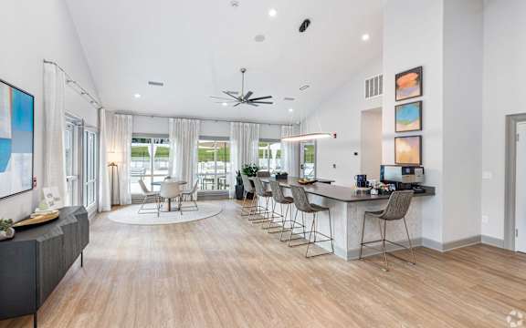 a living room with a kitchen and a bar with chairs