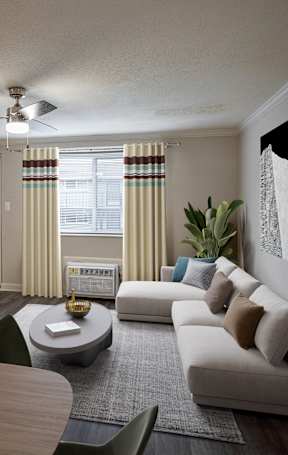 A modern living room with a flat screen TV, a sofa, a coffee table, and a potted plant.