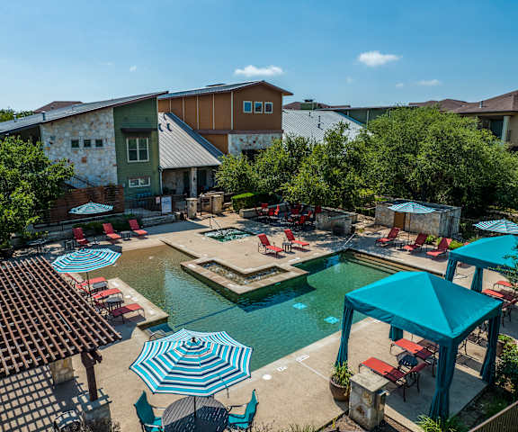 an aerial view of the resort style pool and hot tub with lounge chairs and umbrellas at Lakeline East Apartments, Texas, 78613