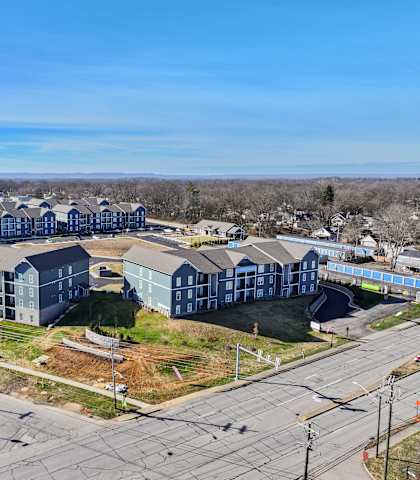 A large, modern apartment complex with multiple buildings and a parking lot in front.