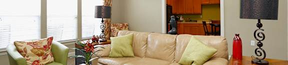A living room with a tan couch, green armchair, and a wooden coffee table.