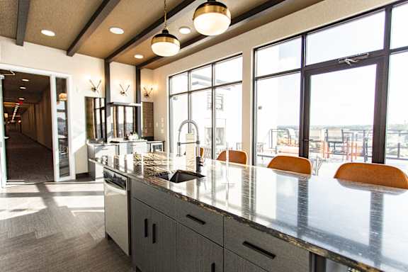 A modern kitchen with a long counter and orange chairs.