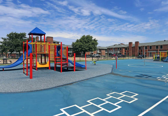 a playground at a school with a basketball court at Williamsburg Apartments, Grand Prairie, 75051