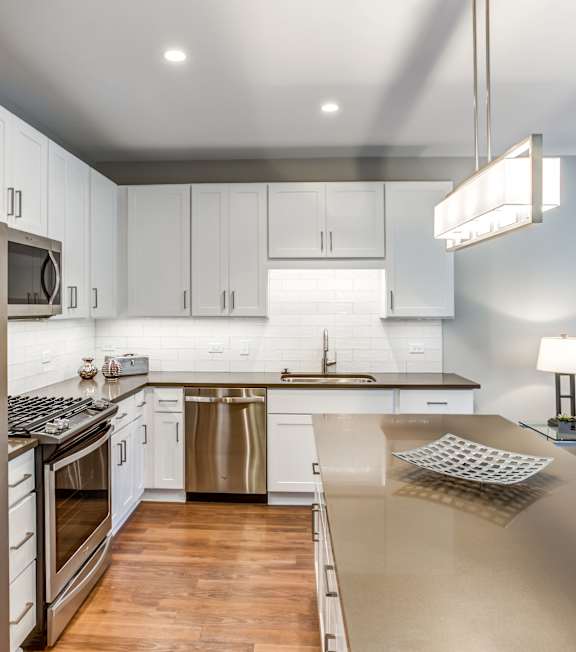 A modern kitchen with a stainless steel refrigerator and wooden flooring.