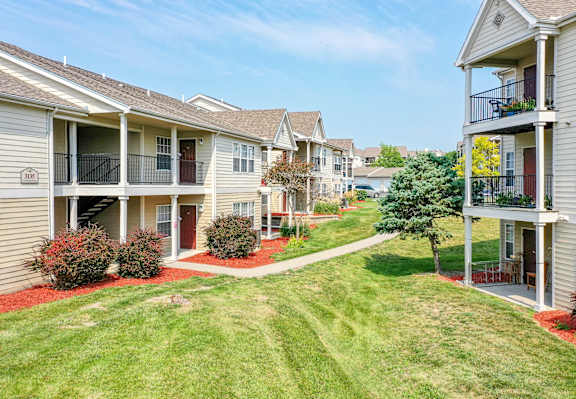 A sunny day at a residential apartment complex with green lawns and red flower beds.