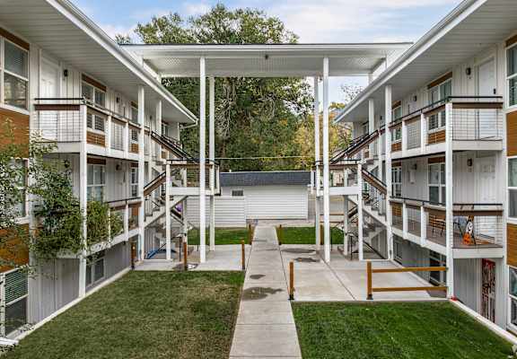 Apartment complex with a white roof and a green lawn.