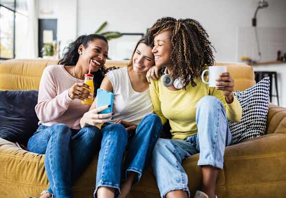 Three friends are sitting on a couch, laughing and enjoying each other's company at Keita 1875, College Park, GA 30349