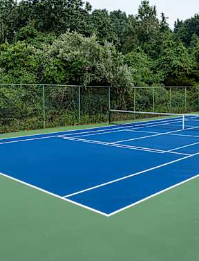 A tennis court surrounded by a green fence.