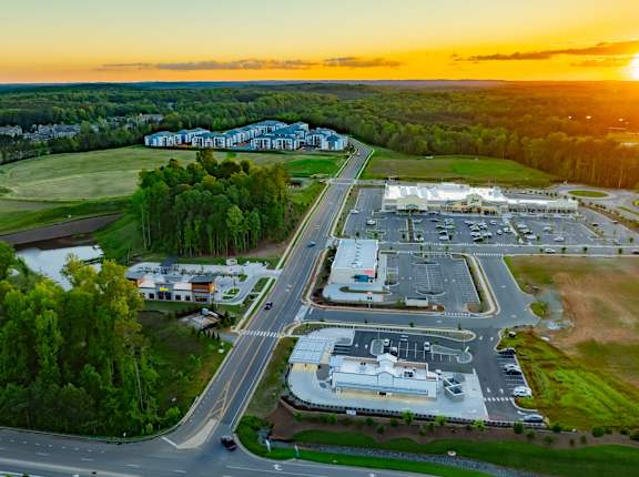 an aerial view of a parking lot and buildings at sunset