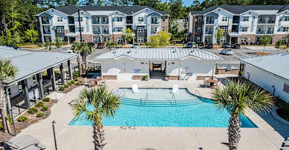 an aerial view of a swimming pool with palm trees in front of an apartment building