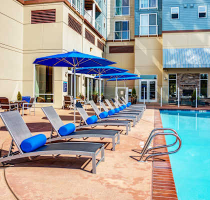 A pool with sun loungers and umbrellas in front of a building.