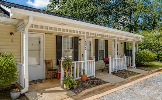 A small house with a porch and a white door.