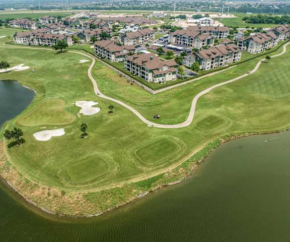 an aerial view of a golf course next to a body of water and a city at The Fairways at Star Ranch, Hutto, Texas