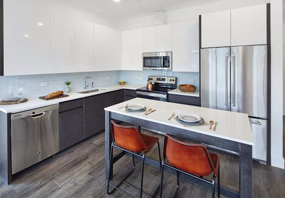 a kitchen with stainless steel appliances and an island with three chairs