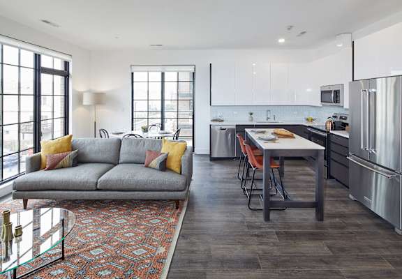 a living room with a couch and a kitchen with stainless steel appliances