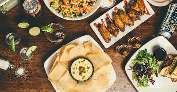 A variety of food including chips and wings are served on a table.