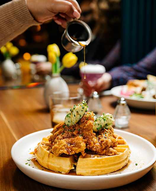 A person pouring sauce on a plate of food.
