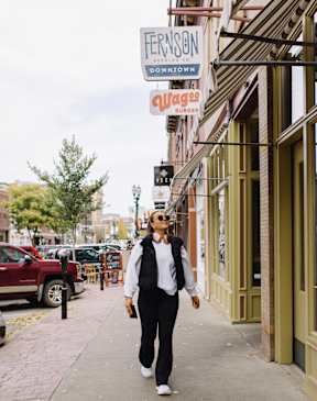 A woman in a white shirt and black pants is walking down a sidewalk.